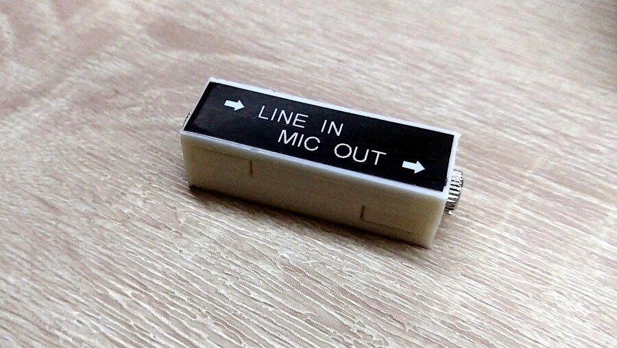 A small white 3d-printed box with a black label that says "line in" and "mic out".